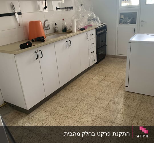 מטבח עם ארונות לבנים ורצפת פרקט בהירה